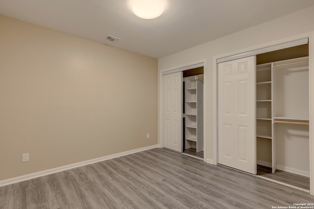 unfurnished bedroom featuring two closets and wood-type flooring