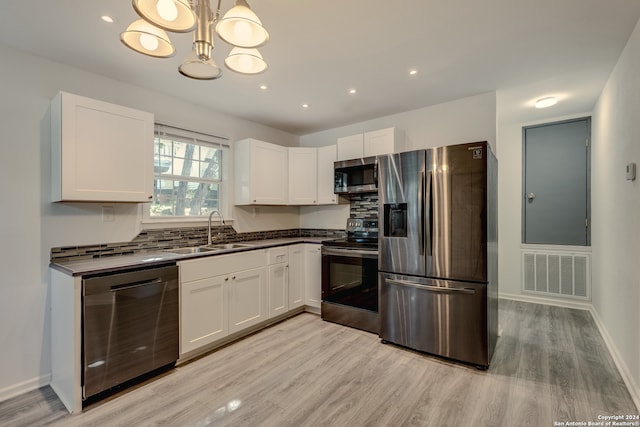 kitchen featuring decorative backsplash, appliances with stainless steel finishes, light hardwood / wood-style floors, sink, and decorative light fixtures