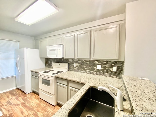 kitchen with light wood-type flooring, sink, decorative backsplash, and white appliances