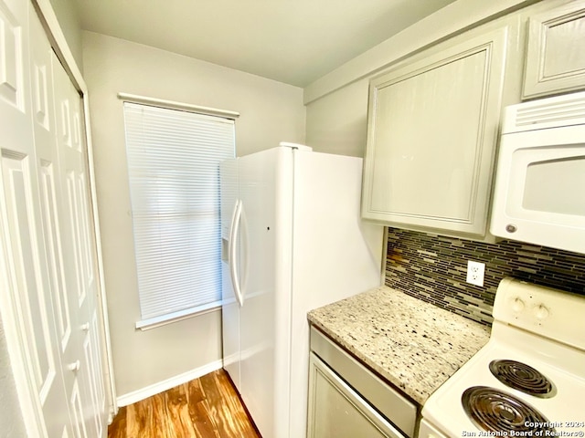 kitchen featuring light hardwood / wood-style flooring, backsplash, cream cabinets, light stone countertops, and white appliances