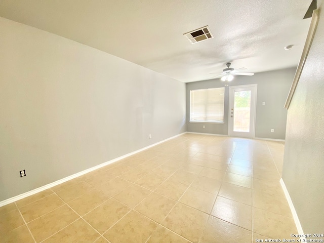 spare room featuring light tile patterned floors, ceiling fan, and a textured ceiling