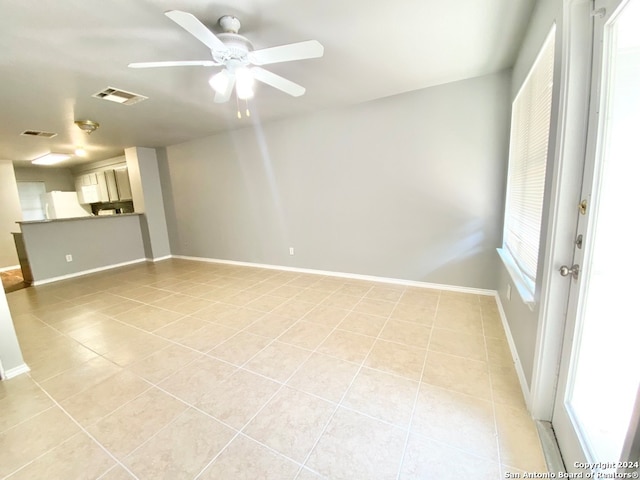 spare room featuring light tile patterned flooring, ceiling fan, and a healthy amount of sunlight