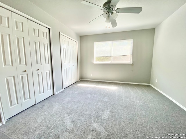 unfurnished bedroom with ceiling fan, two closets, and carpet