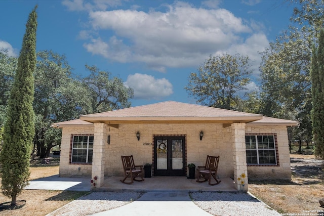 exterior space with a patio area, roof with shingles, and french doors