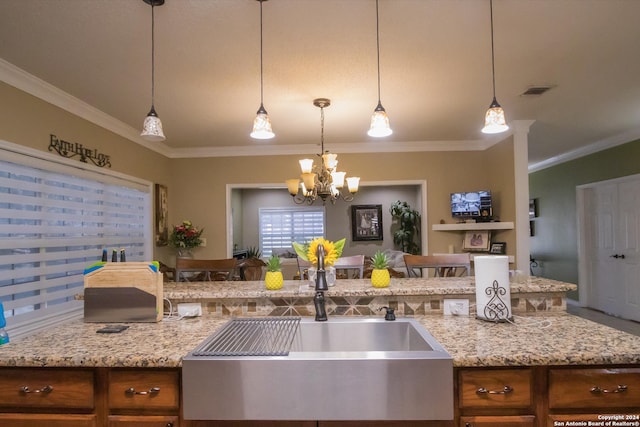 kitchen with hanging light fixtures, crown molding, light stone counters, and a chandelier