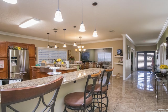 kitchen with light tile patterned flooring, a kitchen breakfast bar, light stone countertops, stainless steel fridge with ice dispenser, and hanging light fixtures