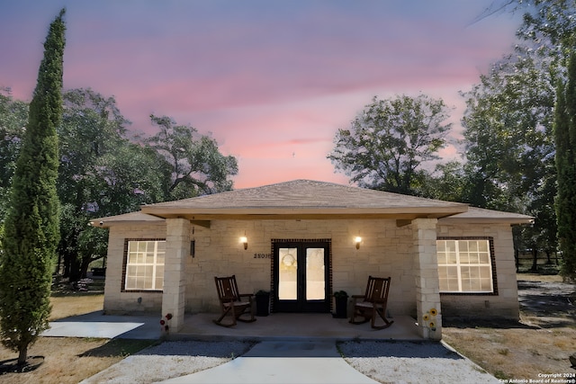 back of property featuring french doors and roof with shingles