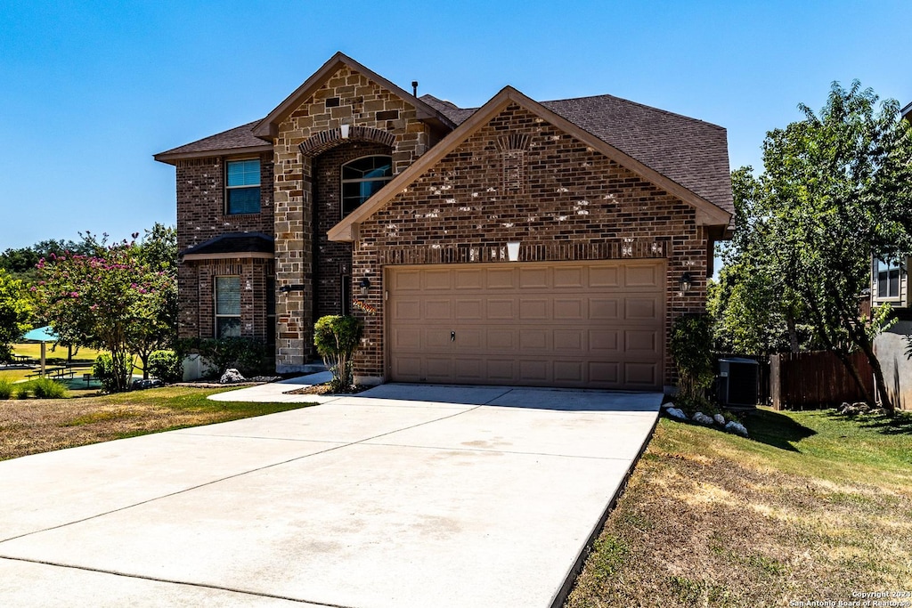 traditional-style house featuring a garage, brick siding, a shingled roof, concrete driveway, and stone siding