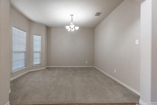 unfurnished room with a notable chandelier and light colored carpet