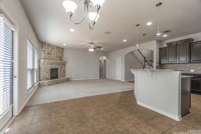 kitchen with a breakfast bar area, hanging light fixtures, carpet floors, and ceiling fan with notable chandelier