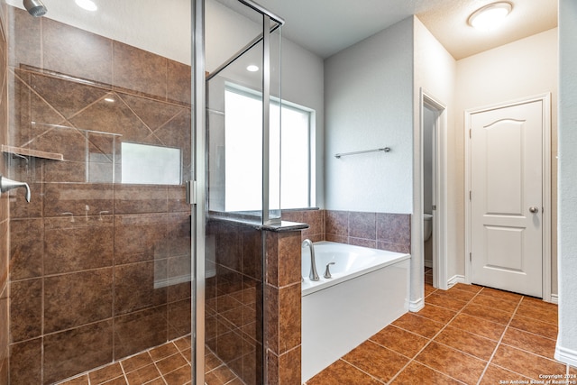 bathroom featuring toilet, tile patterned floors, and separate shower and tub