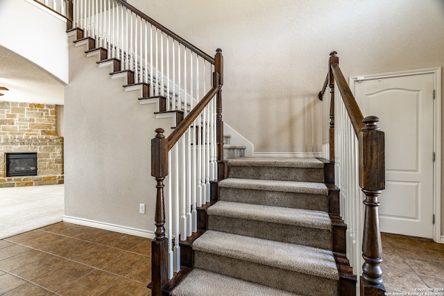 stairs with a stone fireplace and tile patterned flooring