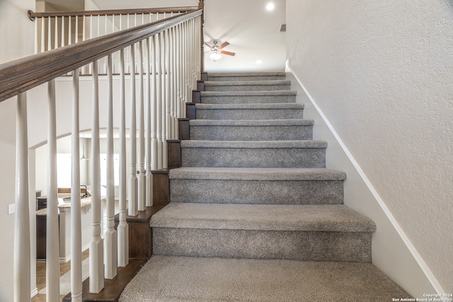 stairs with ceiling fan and hardwood / wood-style flooring