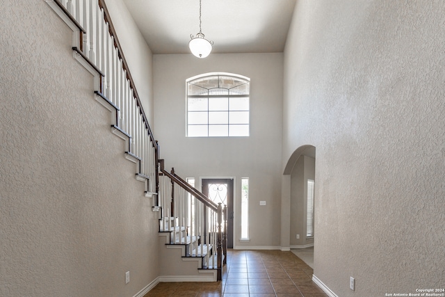 entryway with a high ceiling, dark tile patterned floors, and plenty of natural light