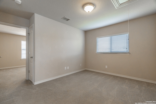 carpeted empty room with a textured ceiling