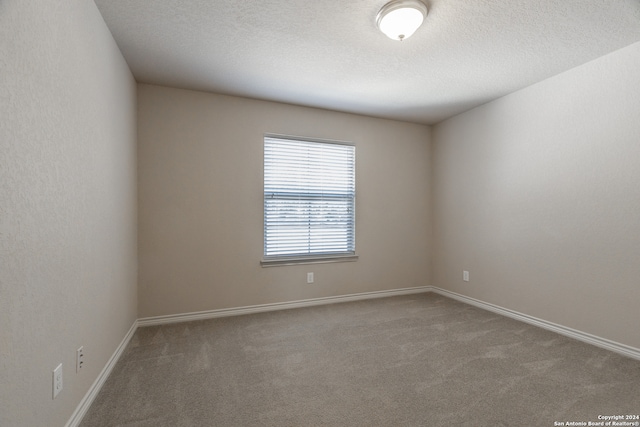 carpeted empty room featuring a textured ceiling