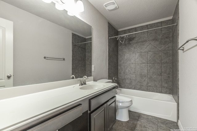 full bathroom with a textured ceiling, toilet, tile patterned floors, tiled shower / bath, and vanity