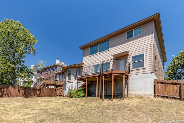 rear view of property featuring a deck and a lawn