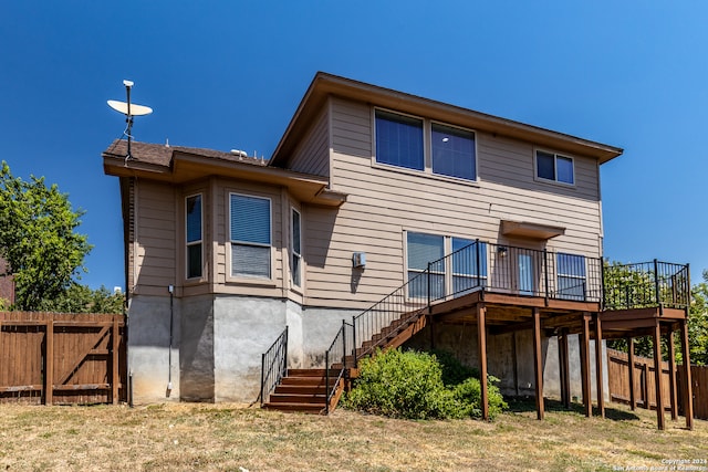 rear view of property featuring a wooden deck and a lawn