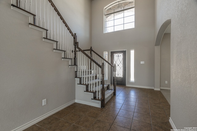 entrance foyer with a towering ceiling and dark tile patterned floors