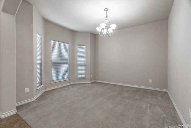 carpeted empty room featuring a notable chandelier