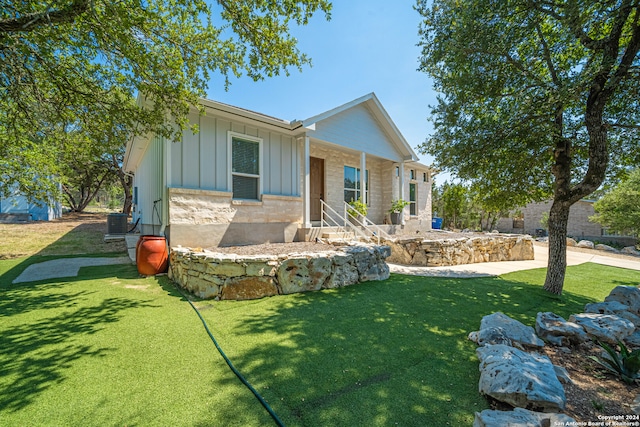 view of front of house with central AC unit and a front yard