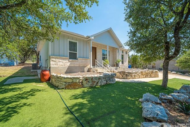 view of front of property with a front lawn, board and batten siding, and central air condition unit