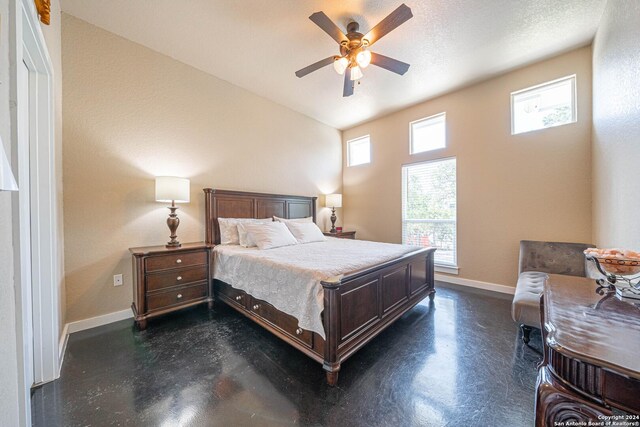 bedroom with a textured ceiling, ceiling fan, multiple windows, and lofted ceiling