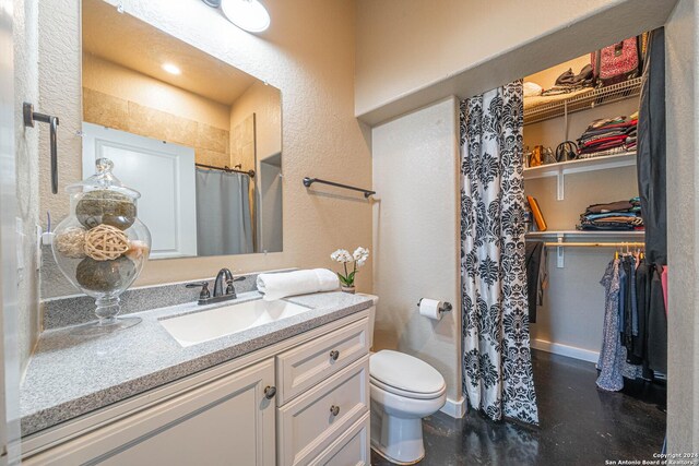 bathroom featuring toilet, walk in shower, and vanity