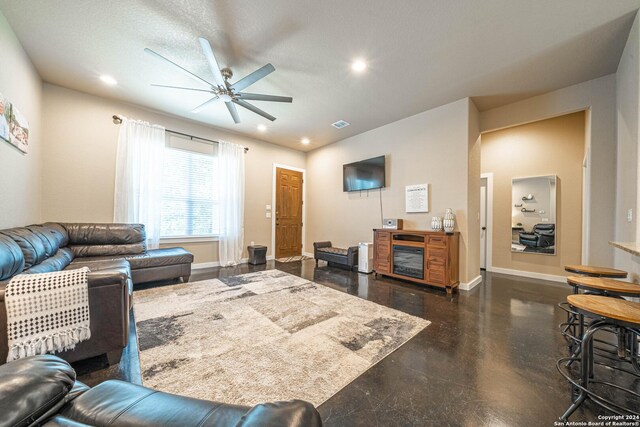 living room featuring ceiling fan and a textured ceiling