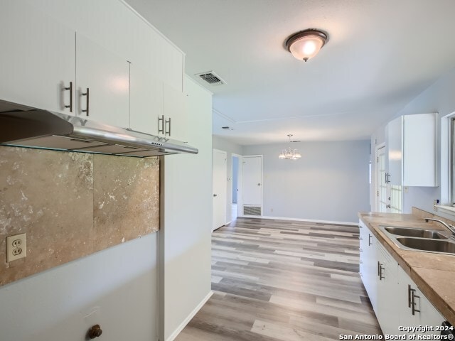 kitchen featuring light wood-type flooring, sink, and white cabinets