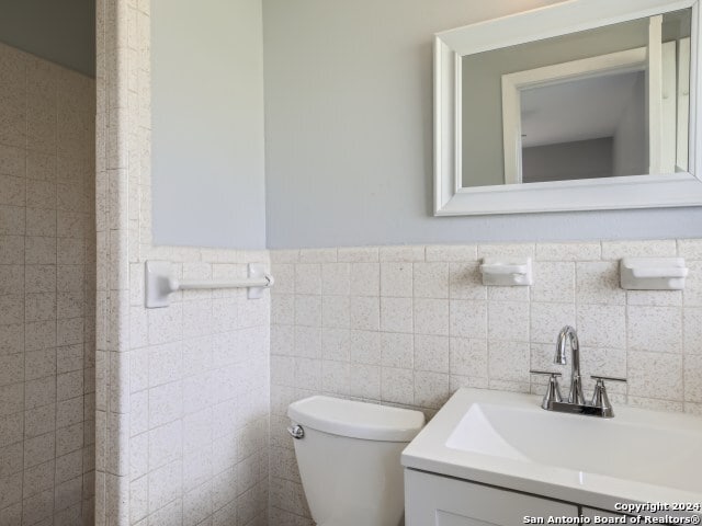 bathroom with backsplash, tile walls, toilet, and vanity