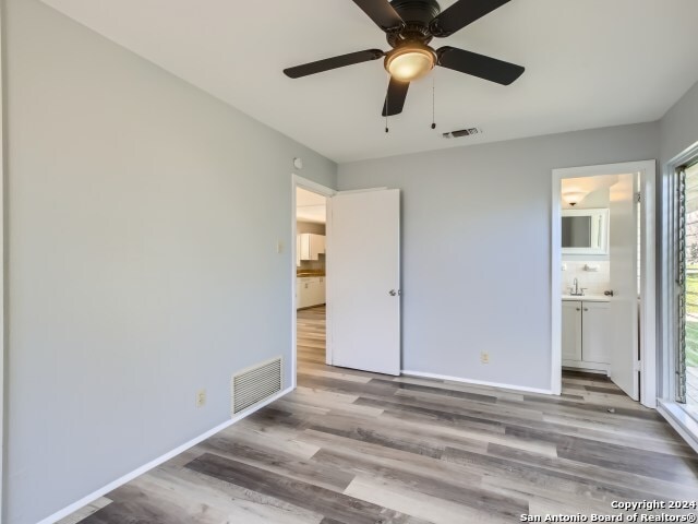 unfurnished bedroom with sink, light hardwood / wood-style flooring, ceiling fan, and ensuite bathroom