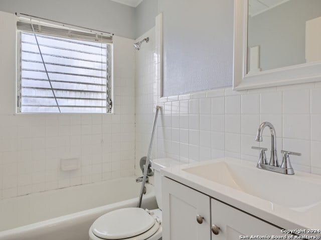 full bathroom featuring decorative backsplash, tiled shower / bath combo, vanity, tile walls, and toilet