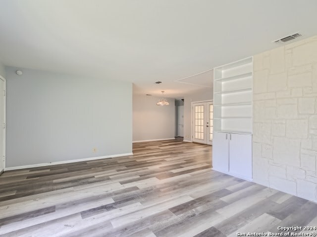 empty room with light hardwood / wood-style floors and an inviting chandelier