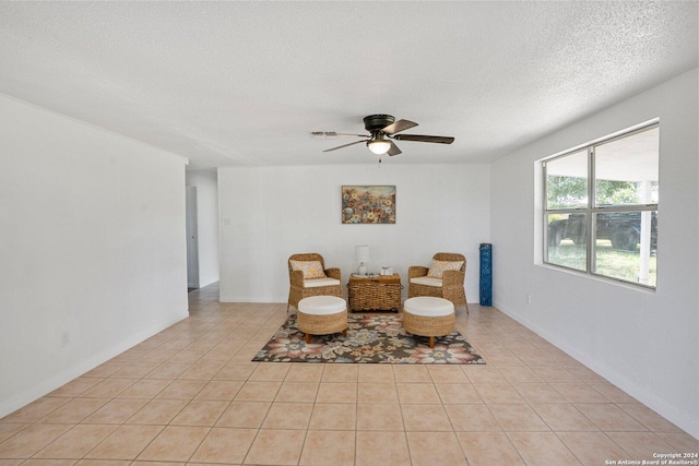 living area featuring a textured ceiling, light tile patterned flooring, baseboards, and ceiling fan