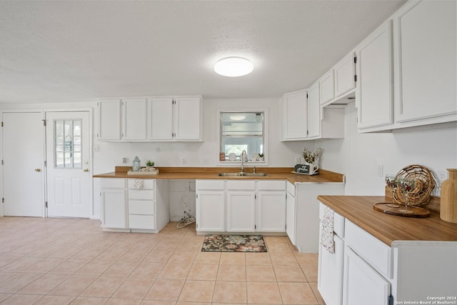 kitchen featuring sink, white cabinetry, light tile patterned flooring, and a wealth of natural light