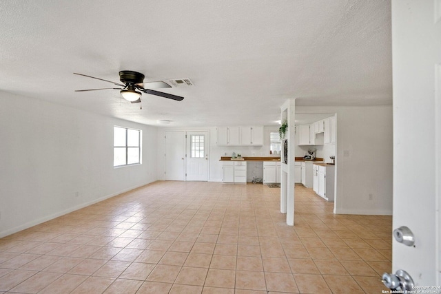 unfurnished living room with visible vents, baseboards, a textured ceiling, and a ceiling fan