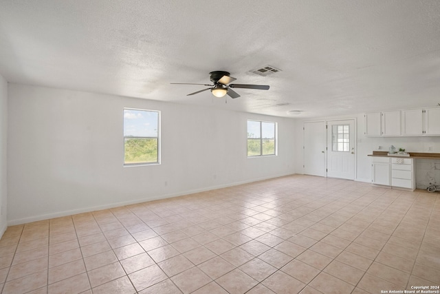 unfurnished living room featuring ceiling fan, a textured ceiling, and light tile patterned floors