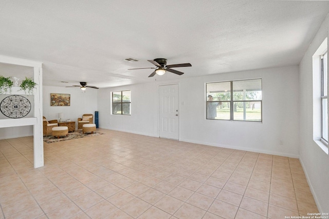 unfurnished living room featuring visible vents, a ceiling fan, a textured ceiling, light tile patterned flooring, and baseboards