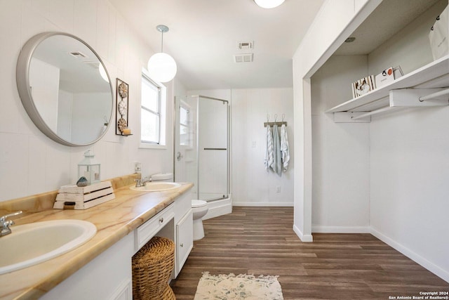 bathroom featuring double vanity, wood finished floors, a stall shower, and a sink