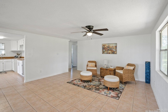 sitting room with light tile patterned floors, a healthy amount of sunlight, a textured ceiling, and a ceiling fan