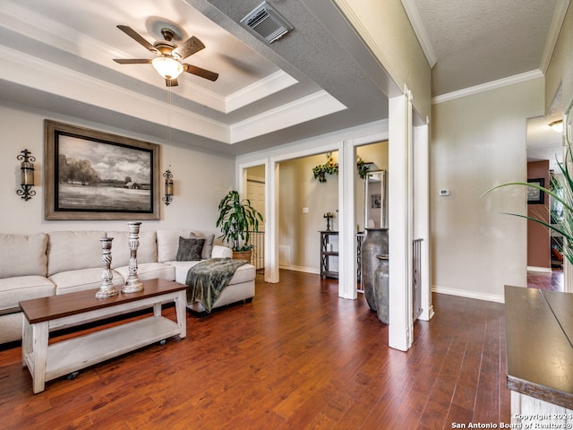 living room featuring ceiling fan, a raised ceiling, dark hardwood / wood-style floors, ornamental molding, and a textured ceiling