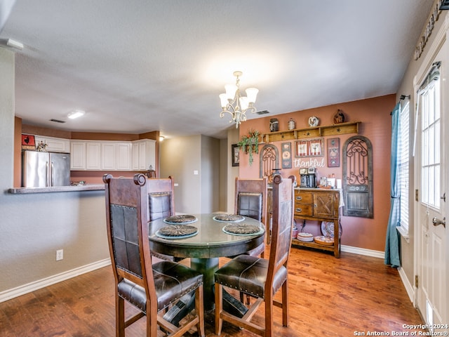 dining room featuring wood-type flooring and an inviting chandelier