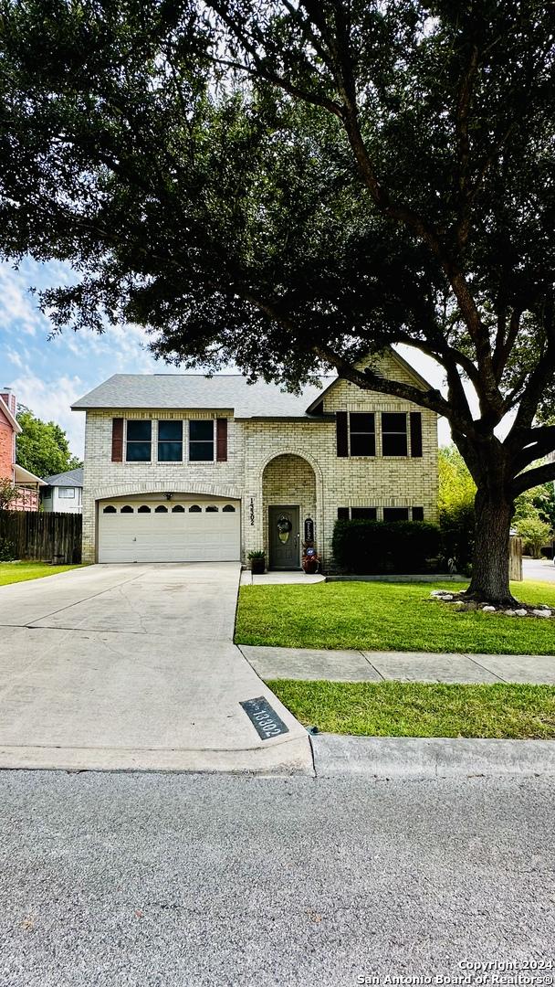 view of front of property featuring driveway, an attached garage, fence, and a front lawn