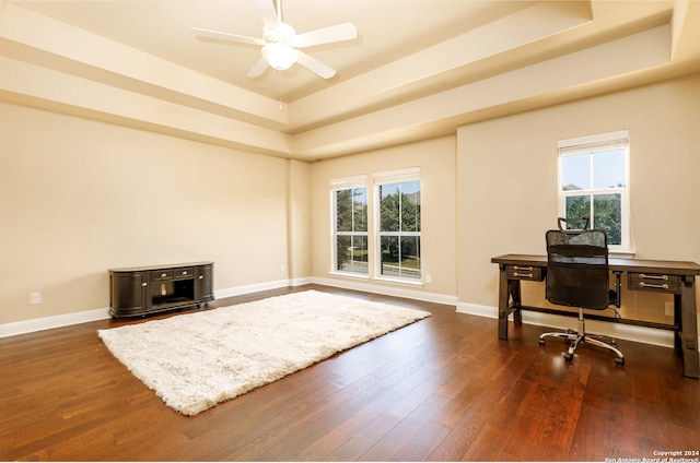 home office featuring ceiling fan, a raised ceiling, and dark wood-type flooring