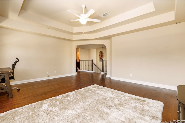 unfurnished office with dark hardwood / wood-style flooring, a raised ceiling, and ceiling fan