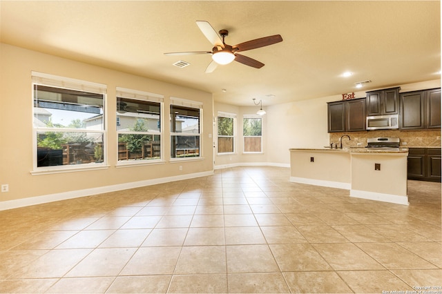 interior space with ceiling fan, backsplash, dark brown cabinetry, pendant lighting, and stove