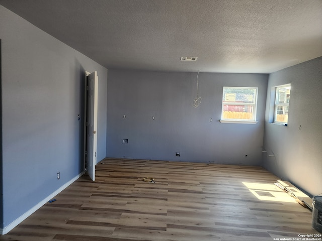 spare room featuring wood-type flooring and a textured ceiling