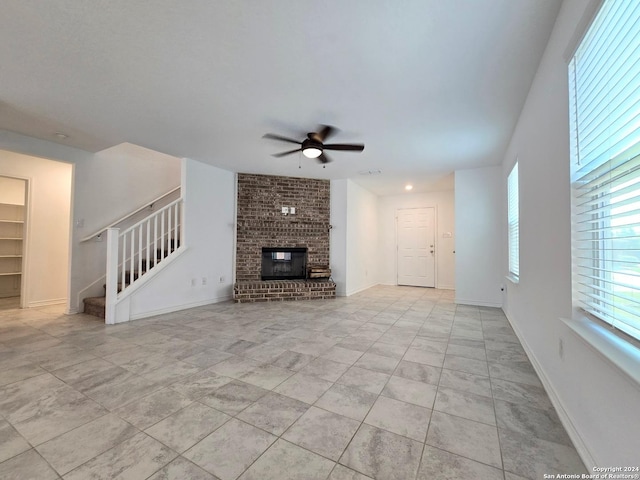 unfurnished living room with built in shelves, a fireplace, a ceiling fan, baseboards, and stairs